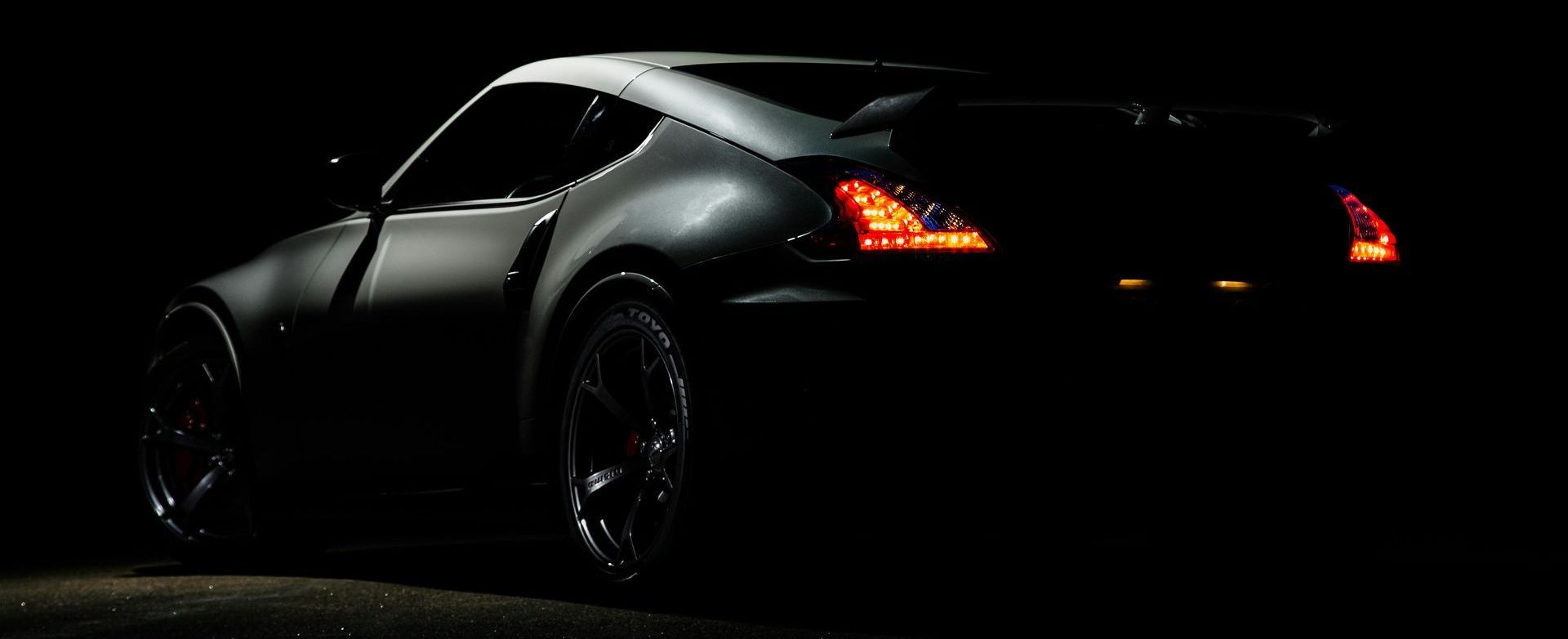 Dark grey sports car at night with illuminated taillights.