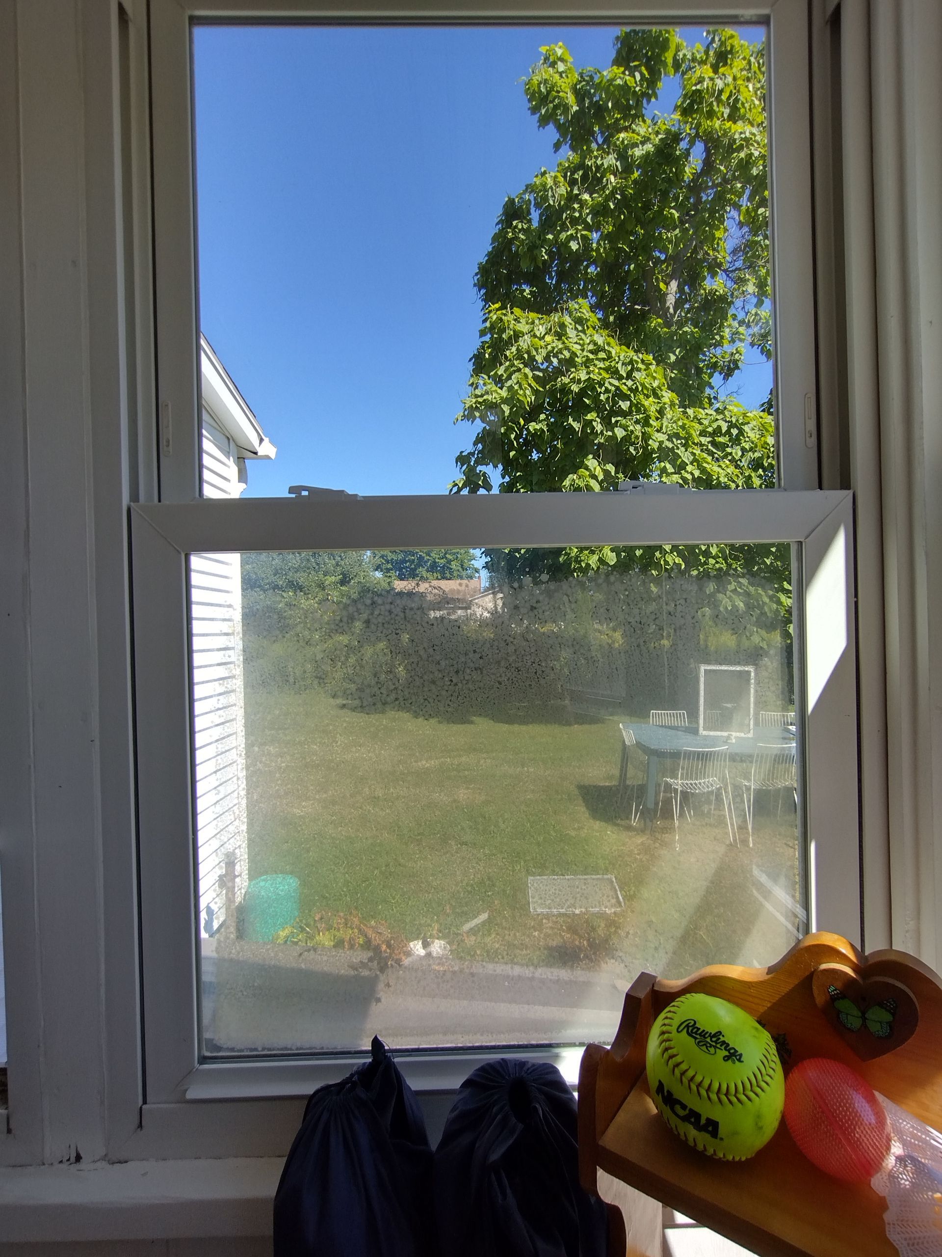 A tennis ball is sitting on a table in front of a window.