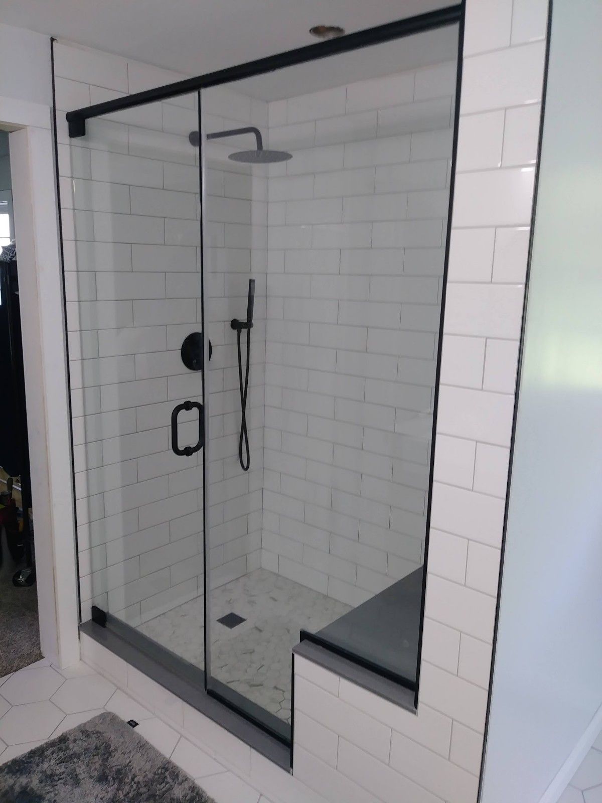 A bathroom with white tiles and a sliding glass shower door