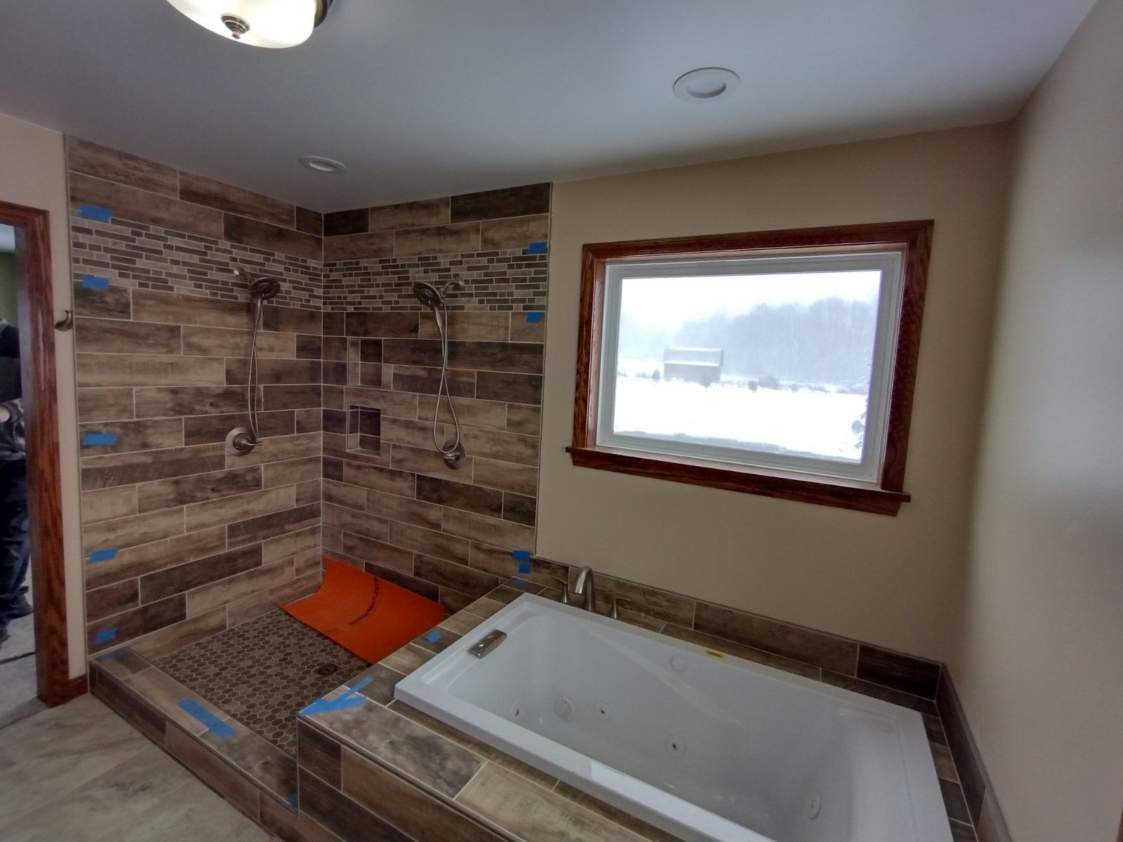 A bathroom with a tub , shower , and window.