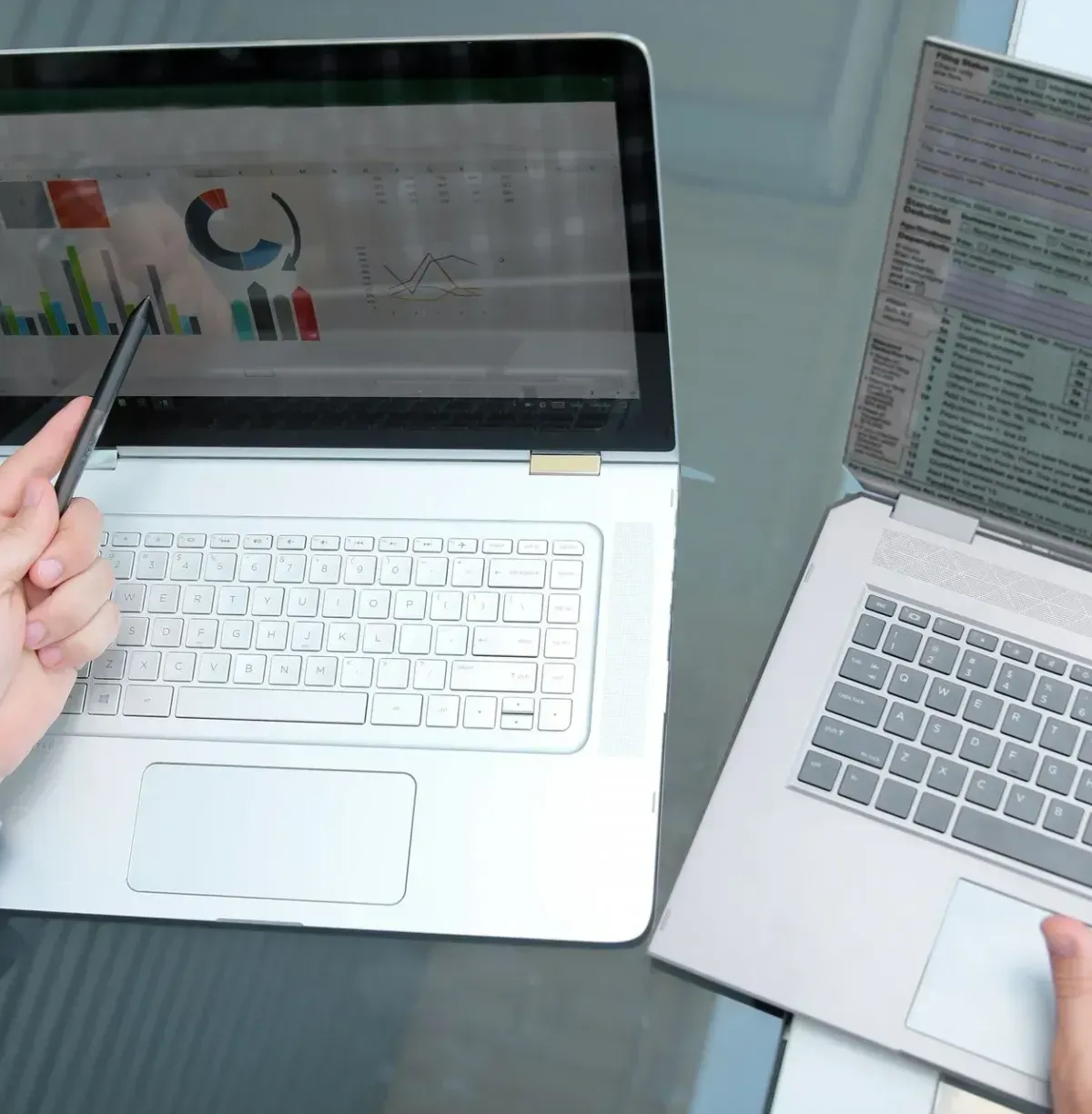 A person is sitting at a table with two laptops and a calculator.