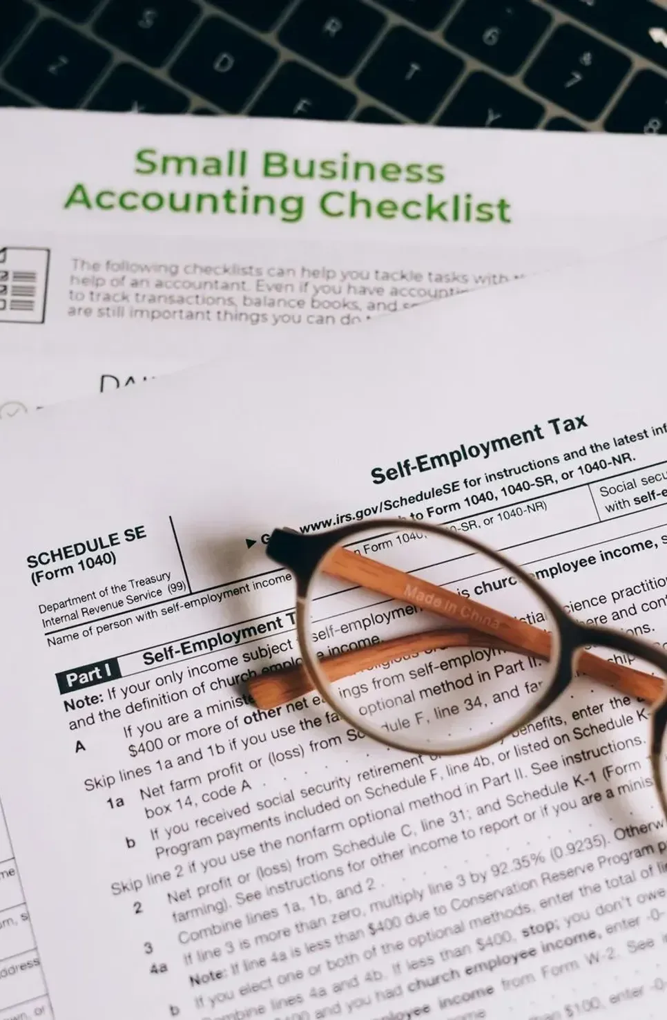 A pair of glasses is sitting on top of a small business accounting checklist.