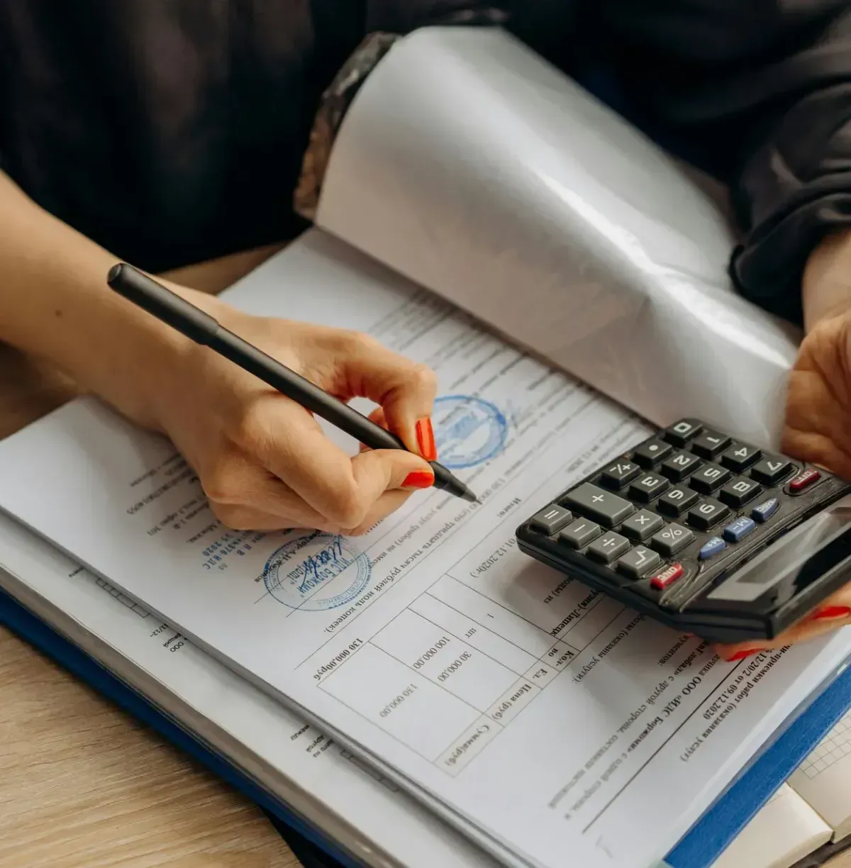 A woman is using a calculator and writing on a piece of paper.