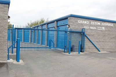 A blue fence is surrounding a building that says grand teton storage.