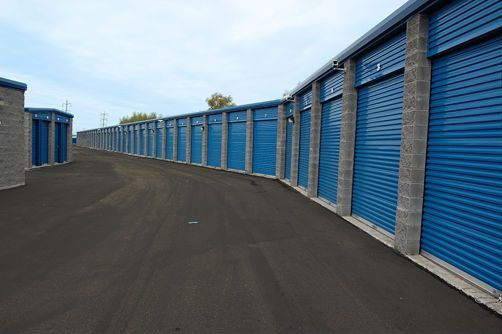 A row of blue storage units are lined up on the side of a road.
