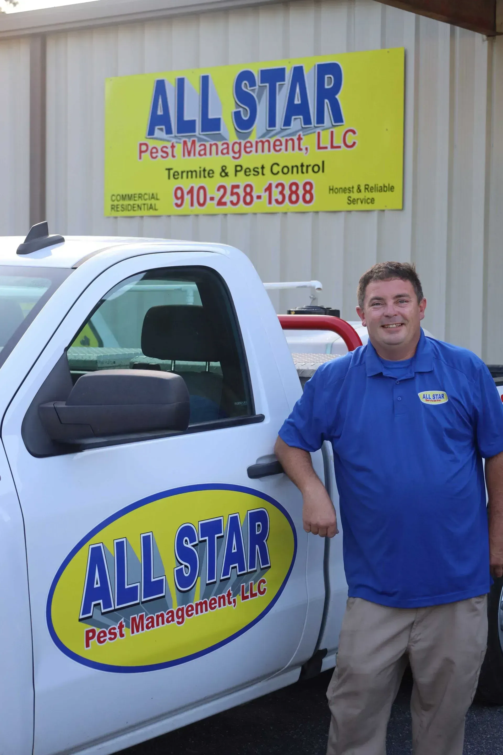 A smiling person in a blue polo shirt leans against a white pickup truck in front of an All Star Pest Management sign.