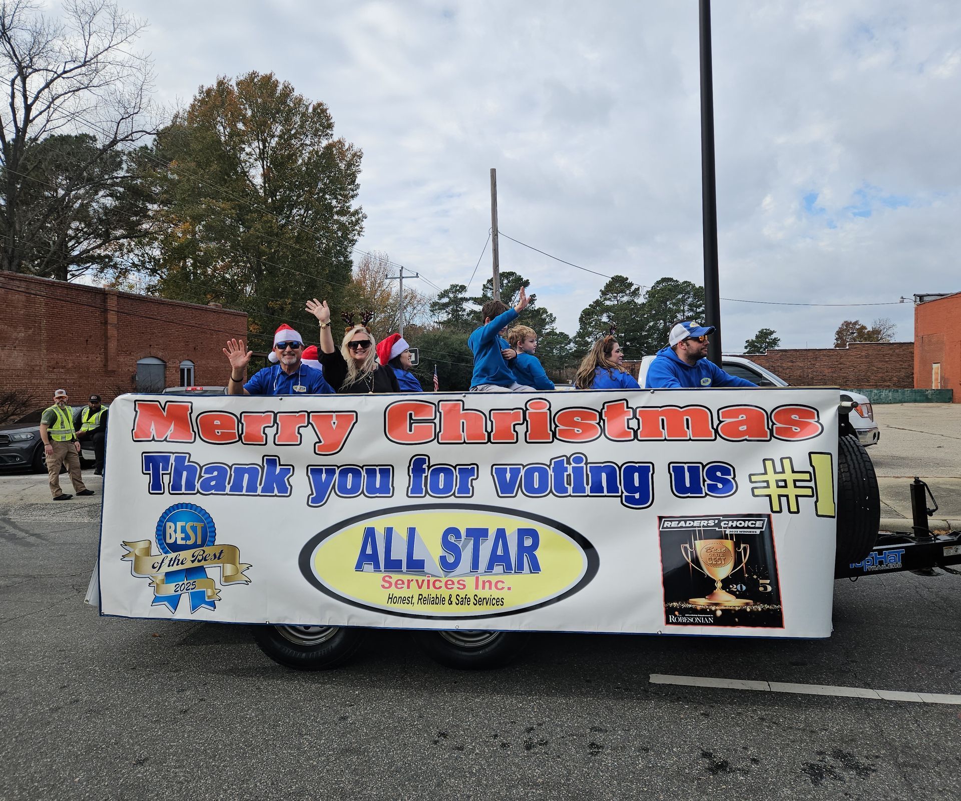 A float in a parade with people waving, featuring a banner that says