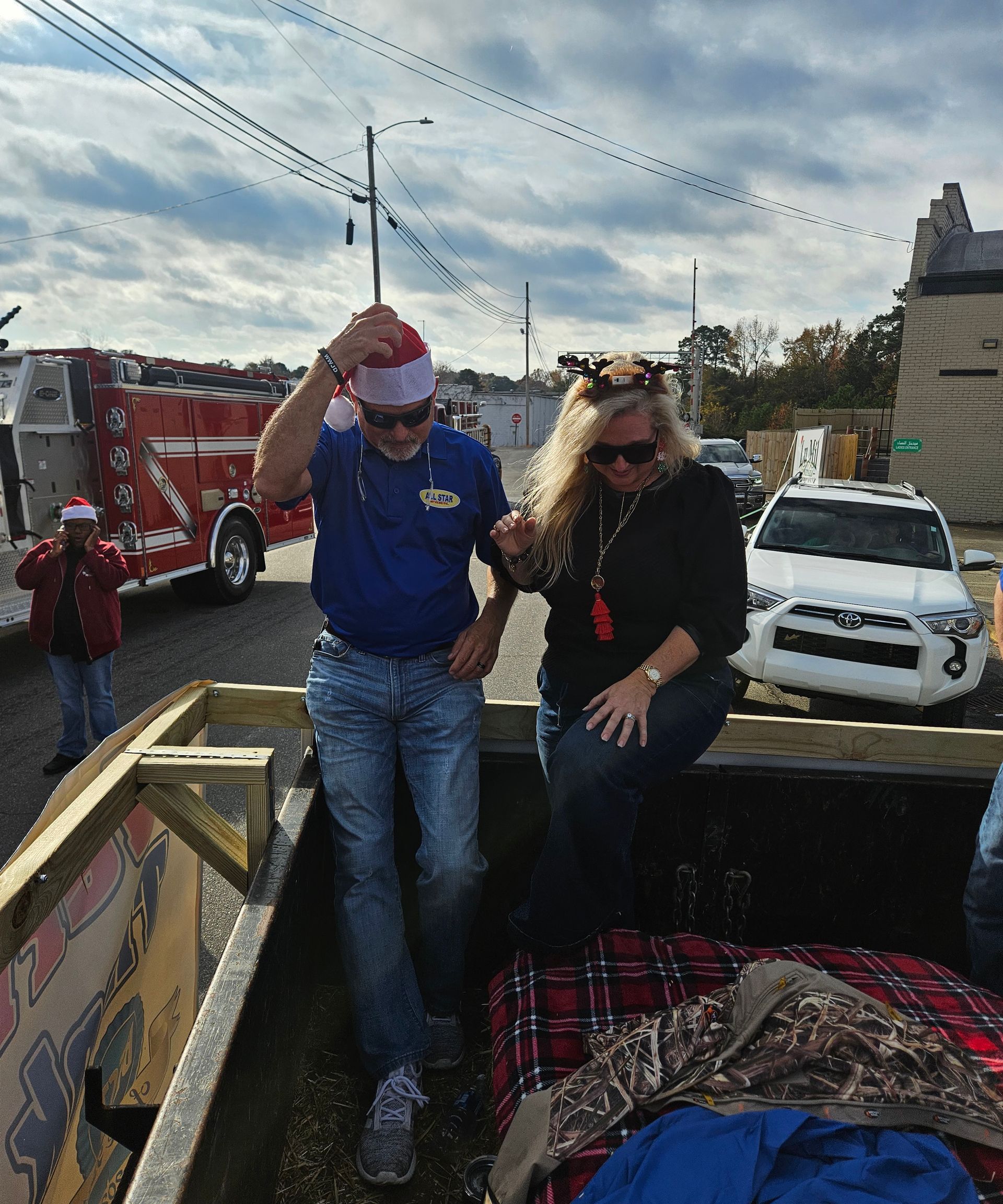 A man in a blue shirt and a woman in black sit on a decorated parade float outdoors on a sunny day.