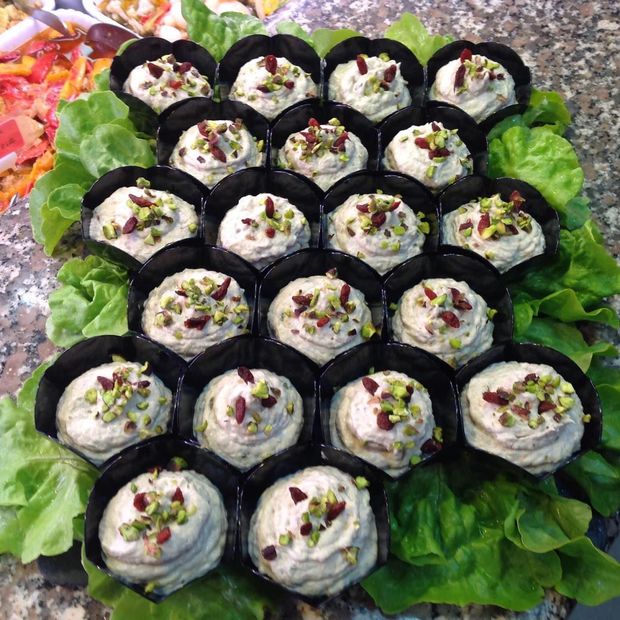 Antipasti in tazze nere, guarniti con noci e frutti di bosco, su lattuga.