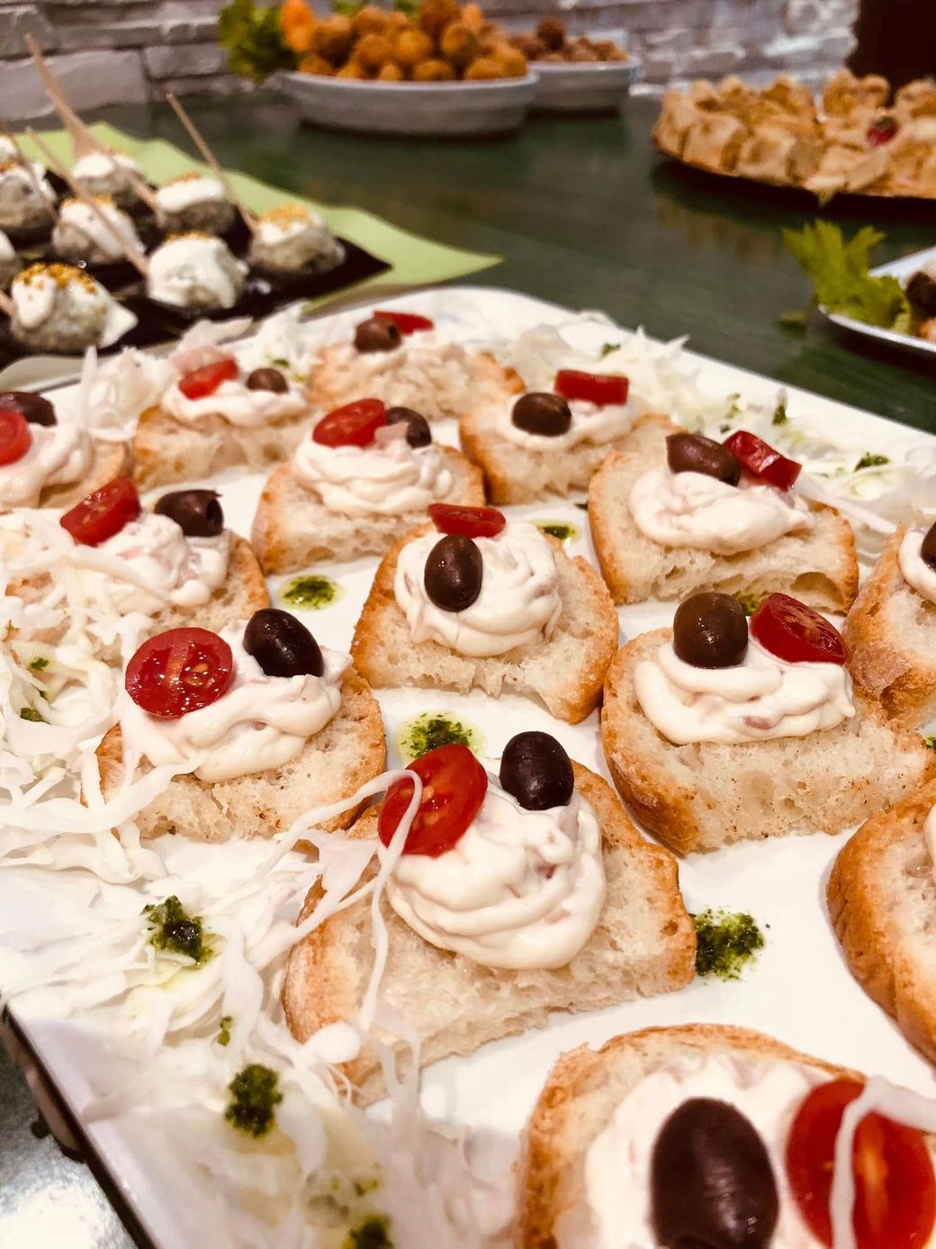 Antipasti su vassoio: pane tostato con crema, olive e pomodori.