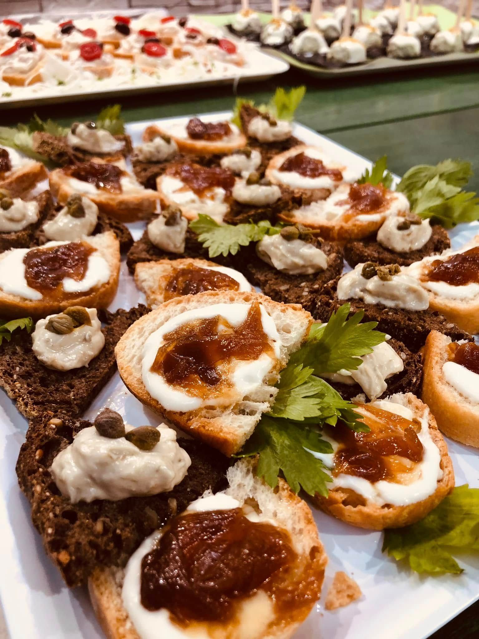 Piatto di antipasti assortiti su piatti bianchi: pane tostato con formaggio, marmellata e capperi.