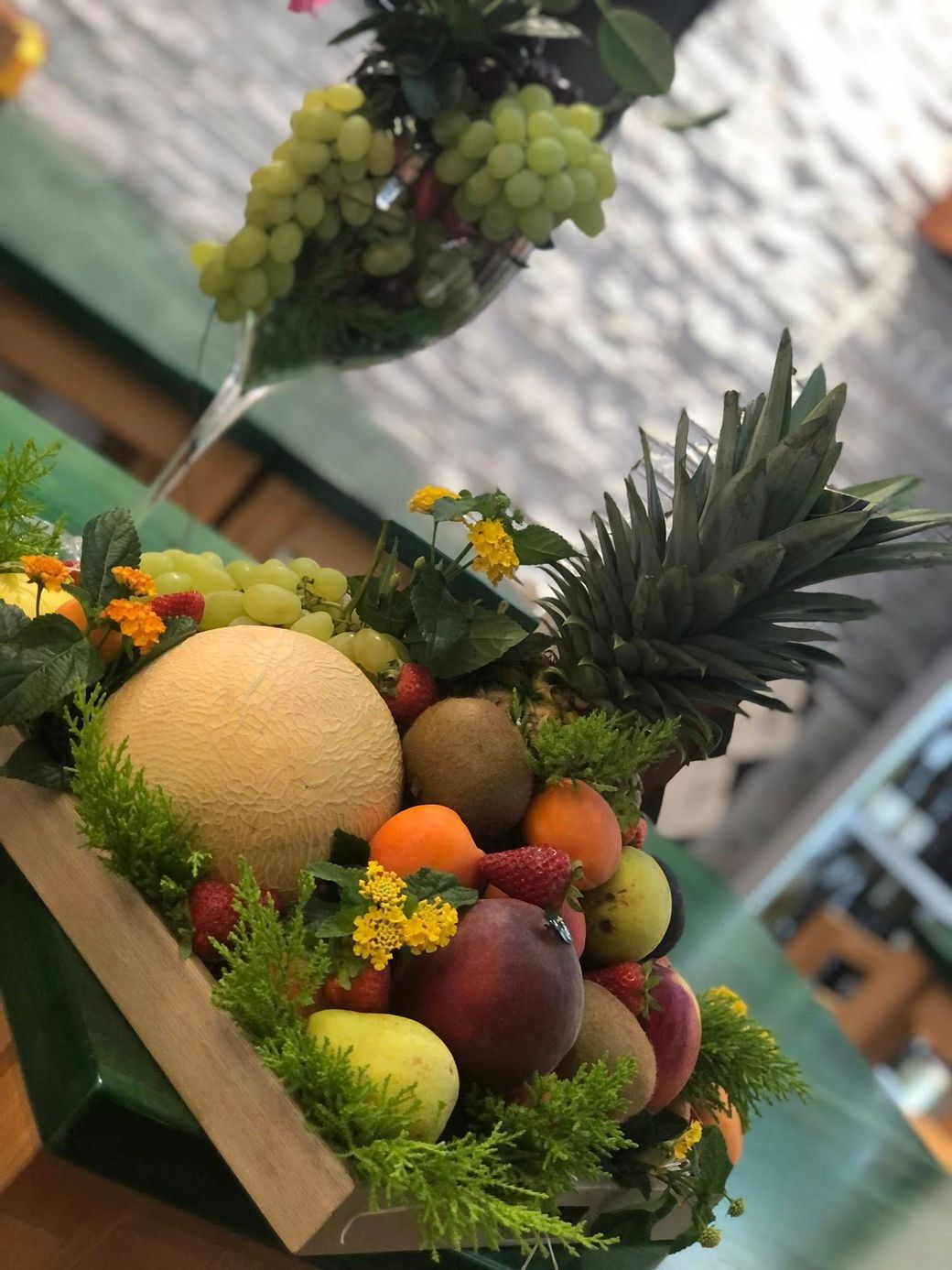 Cesto di frutta con melone, ananas, uva e altri frutti.