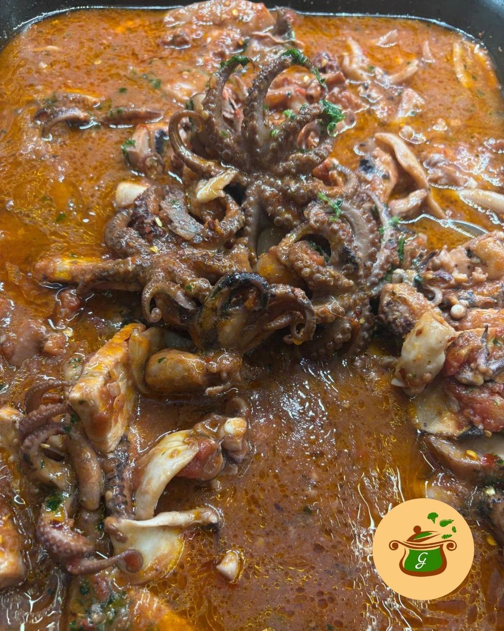 Stufato di pesce con polpo e calamari in salsa di pomodoro. Marrone, rosso e bianco.