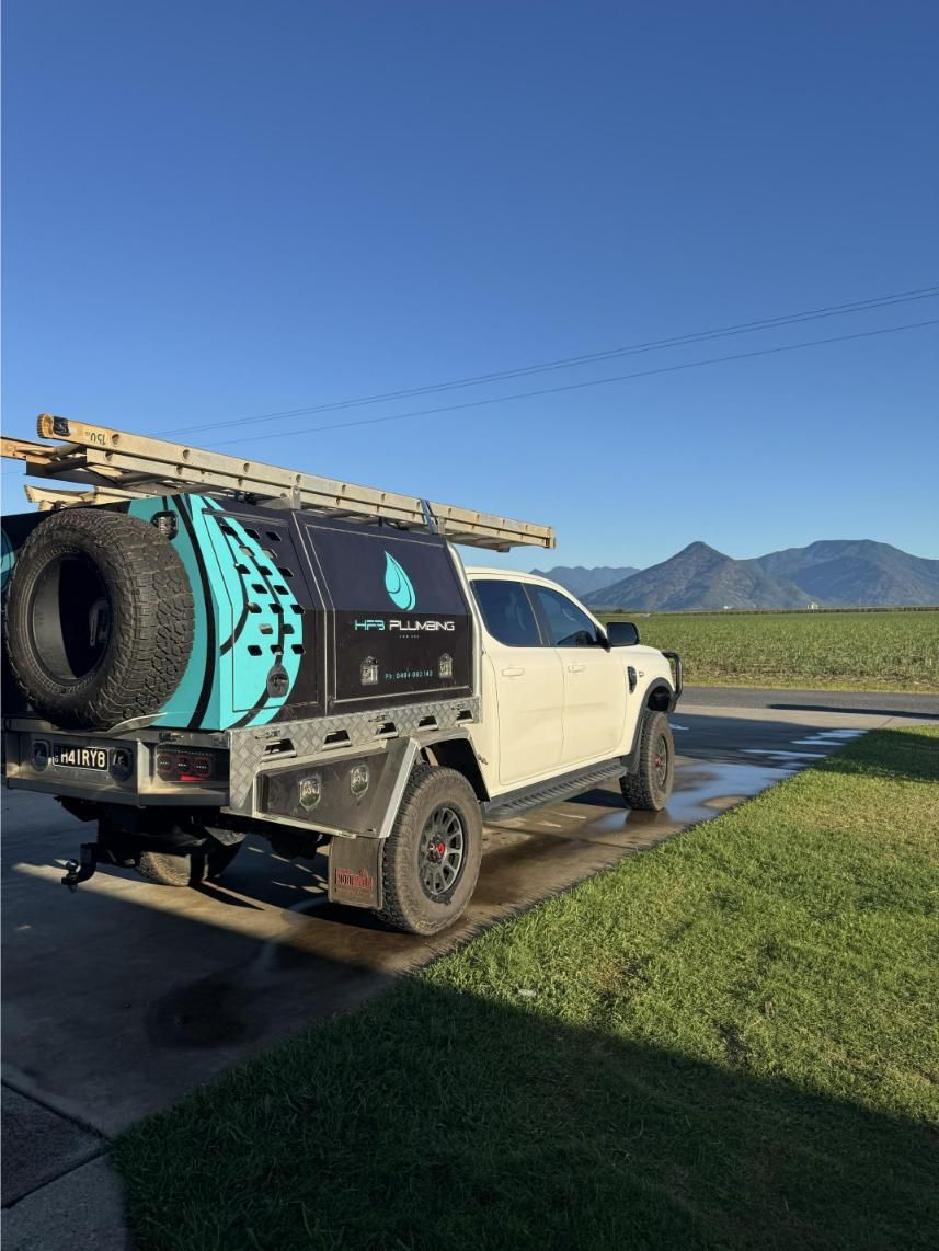 White Truck With a Utility Bed, Ladder, and Spare Tire, Parked on a Driveway — HFB Plumbing & Gas in Edmonton, QLD