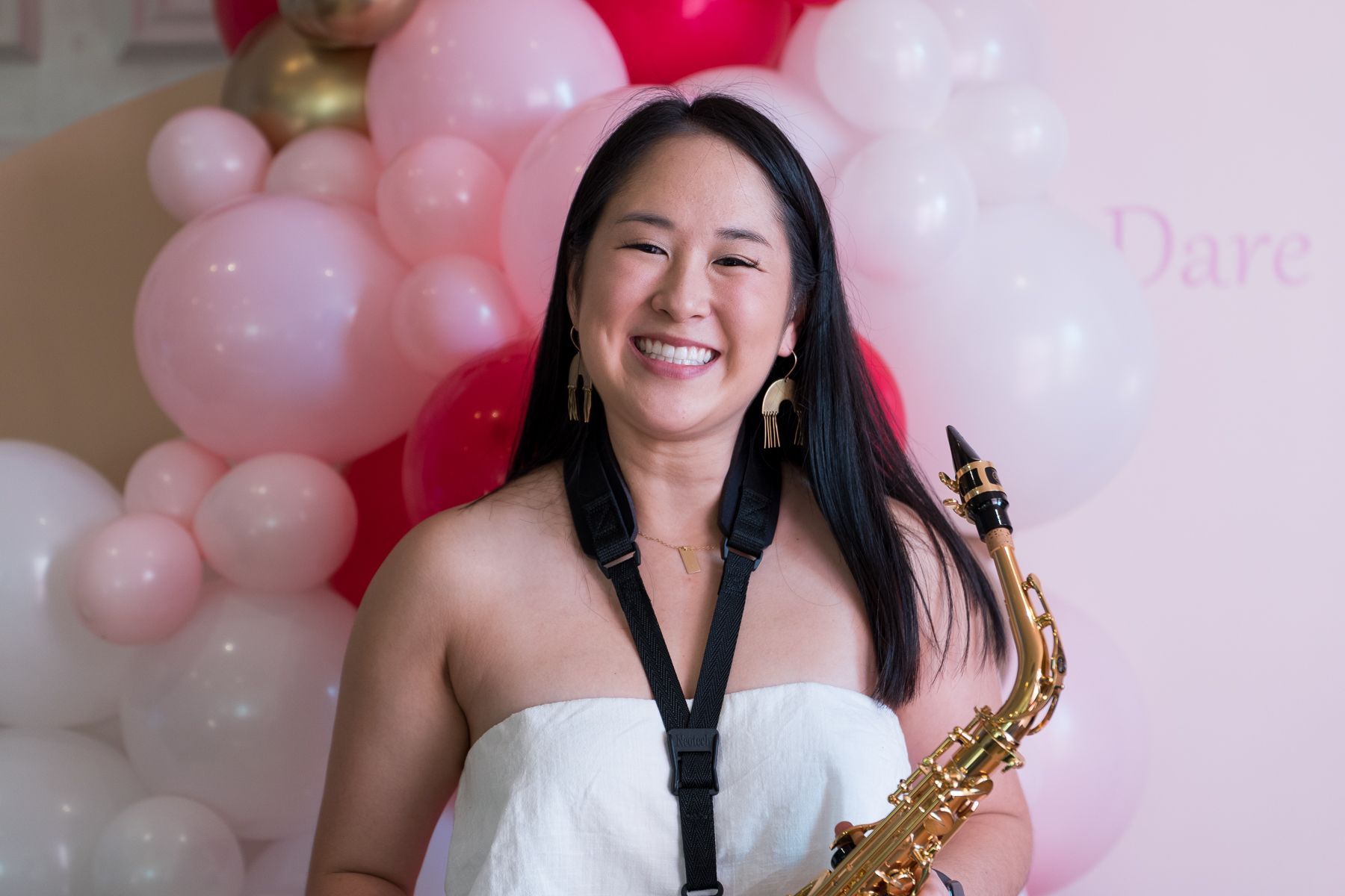 DJ Emily Gracie with her Sax in front of pink balloons