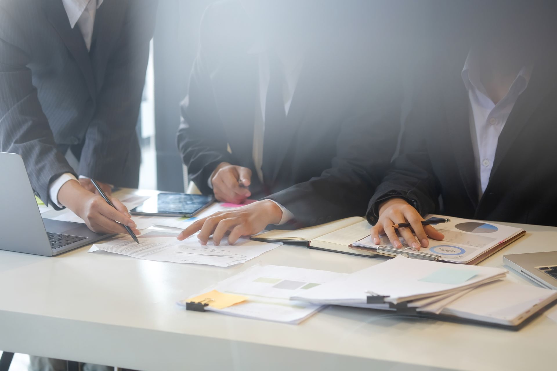 Business people in suits collaborating at a desk, reviewing documents and data.