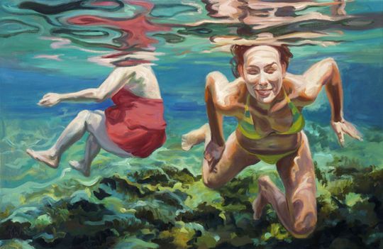 Zwei Personen schwimmen unter Wasser in klarem, flachem Wasser über einem felsigen, grünlichen Grund.