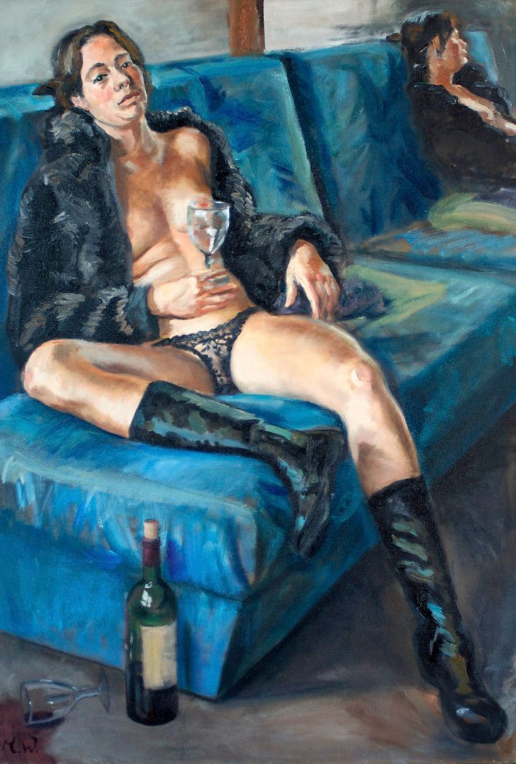 Eine Person, die in einen Pelzmantel und Stiefel gehüllt auf einem blauen Sofa liegt und ein Glas in der Hand hält.