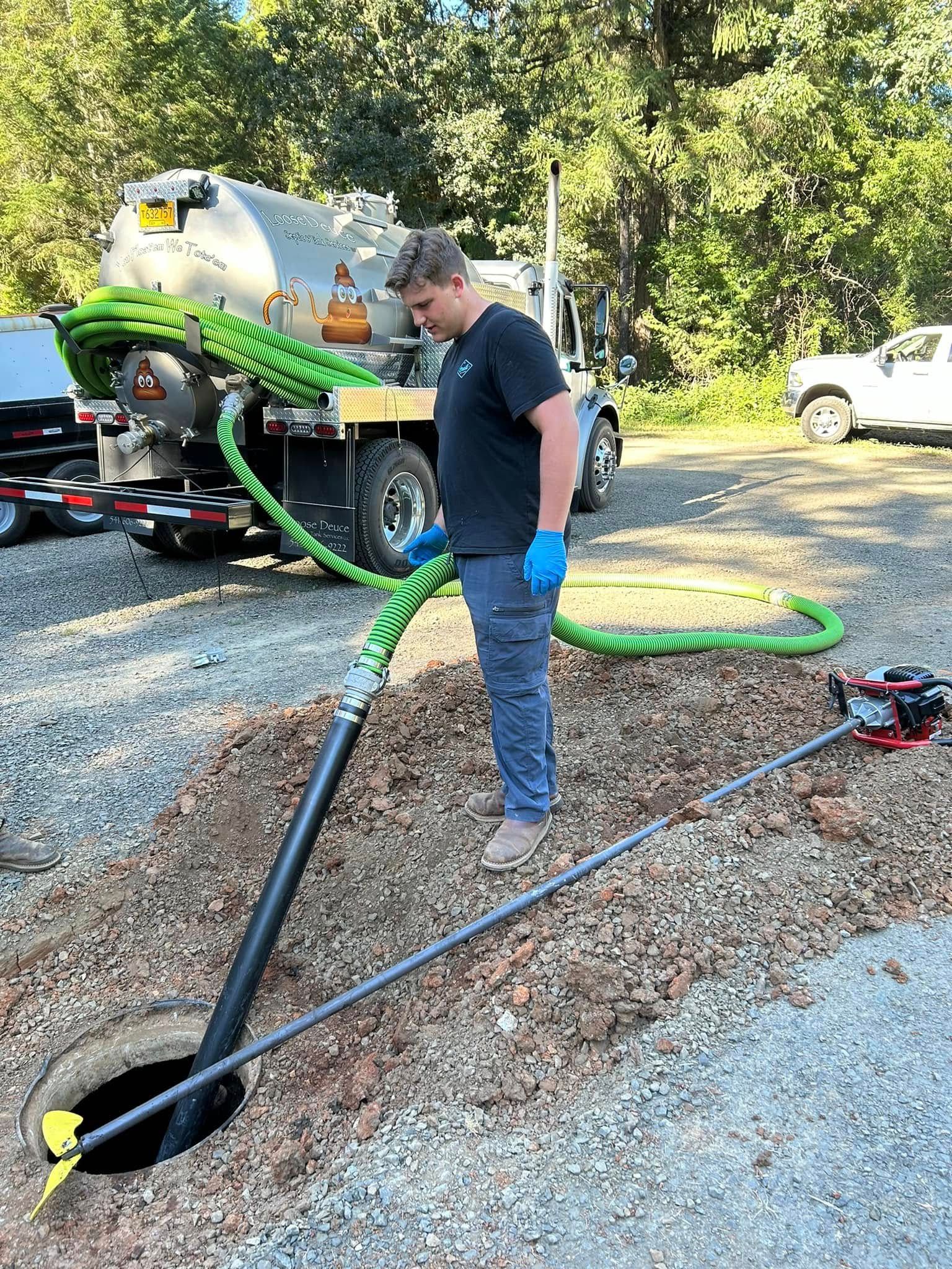 The back of a vacuum truck with a green hose attached to it.