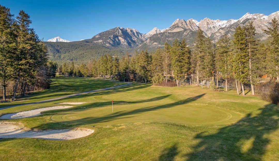 A train is going over a bridge with mountains in the background.