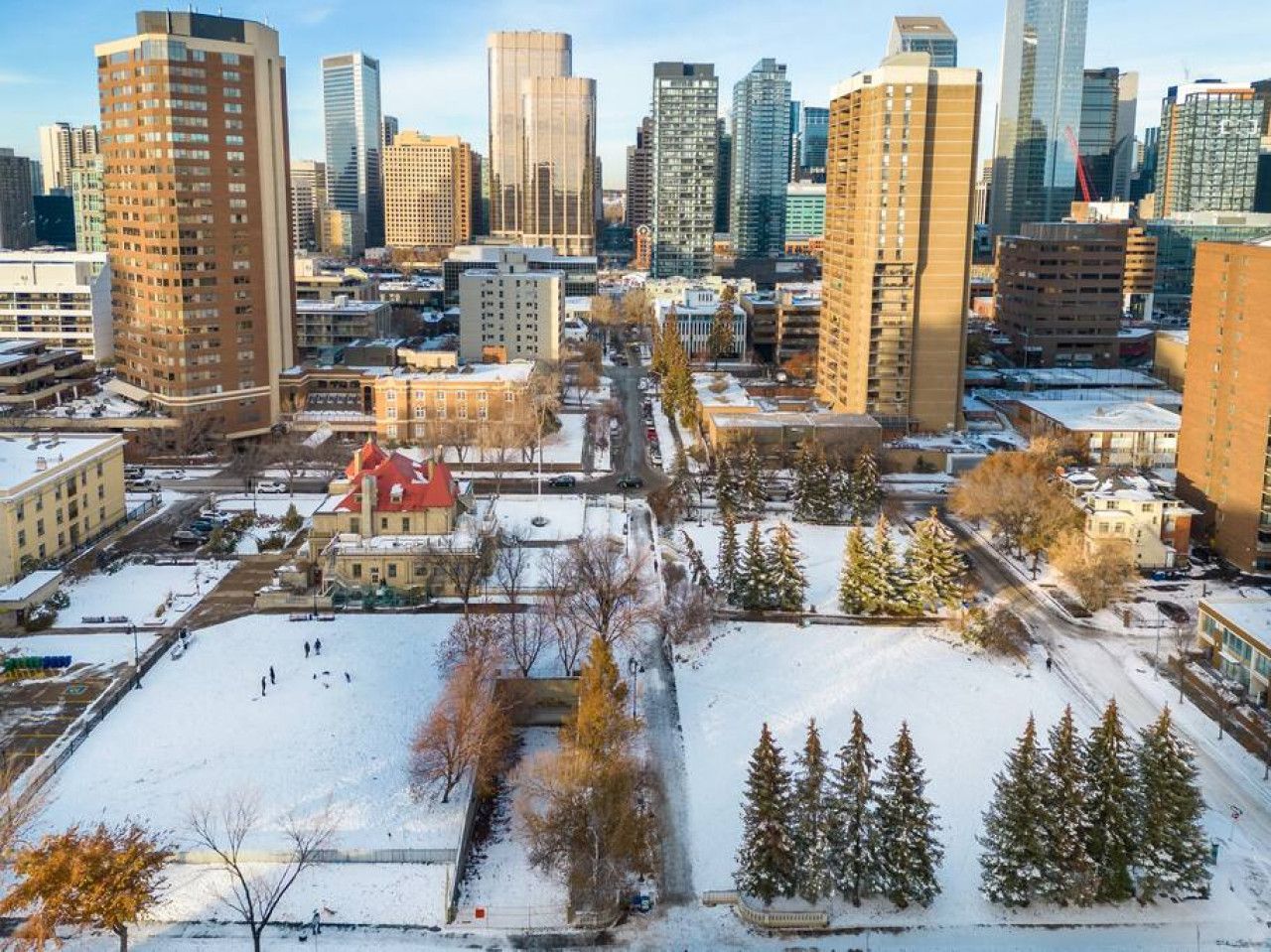An aerial view of a city with snow on the ground and trees in the foreground.