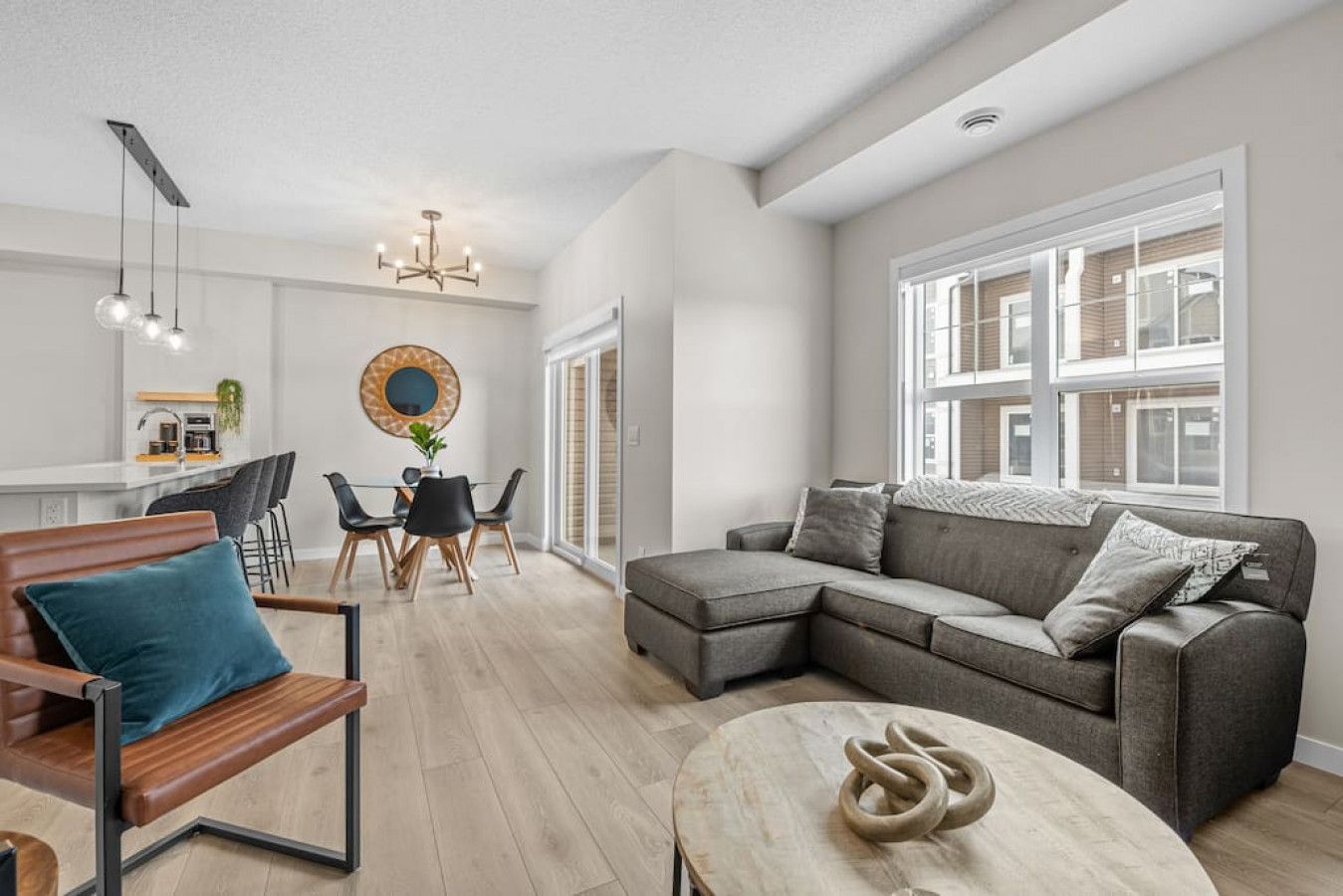 Row of suburban townhouses with a central tan house, driveway, and patches of snow on the ground