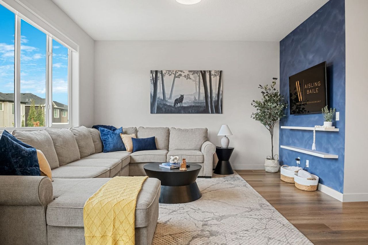 Row of suburban townhouses with a central tan house, driveway, and patches of snow on the ground