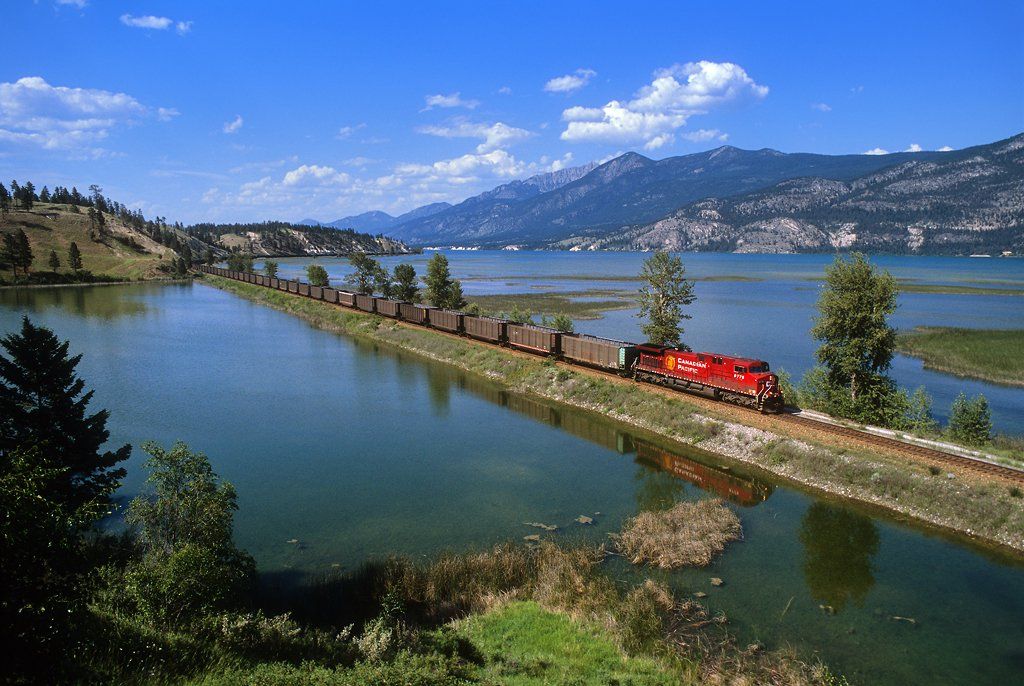 A train is going down the tracks next to a body of water.