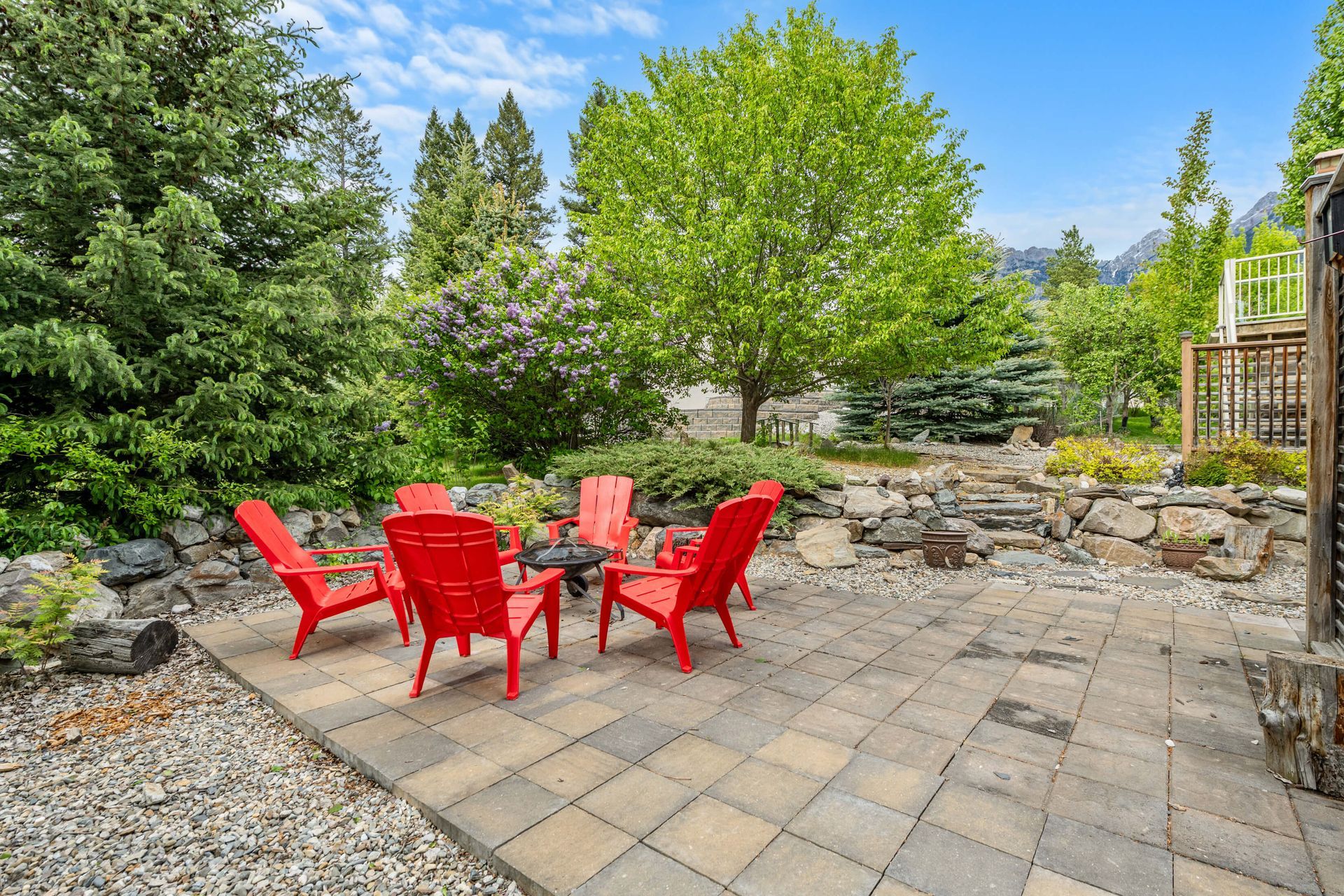A patio with red chairs , a table , and a fire pit.