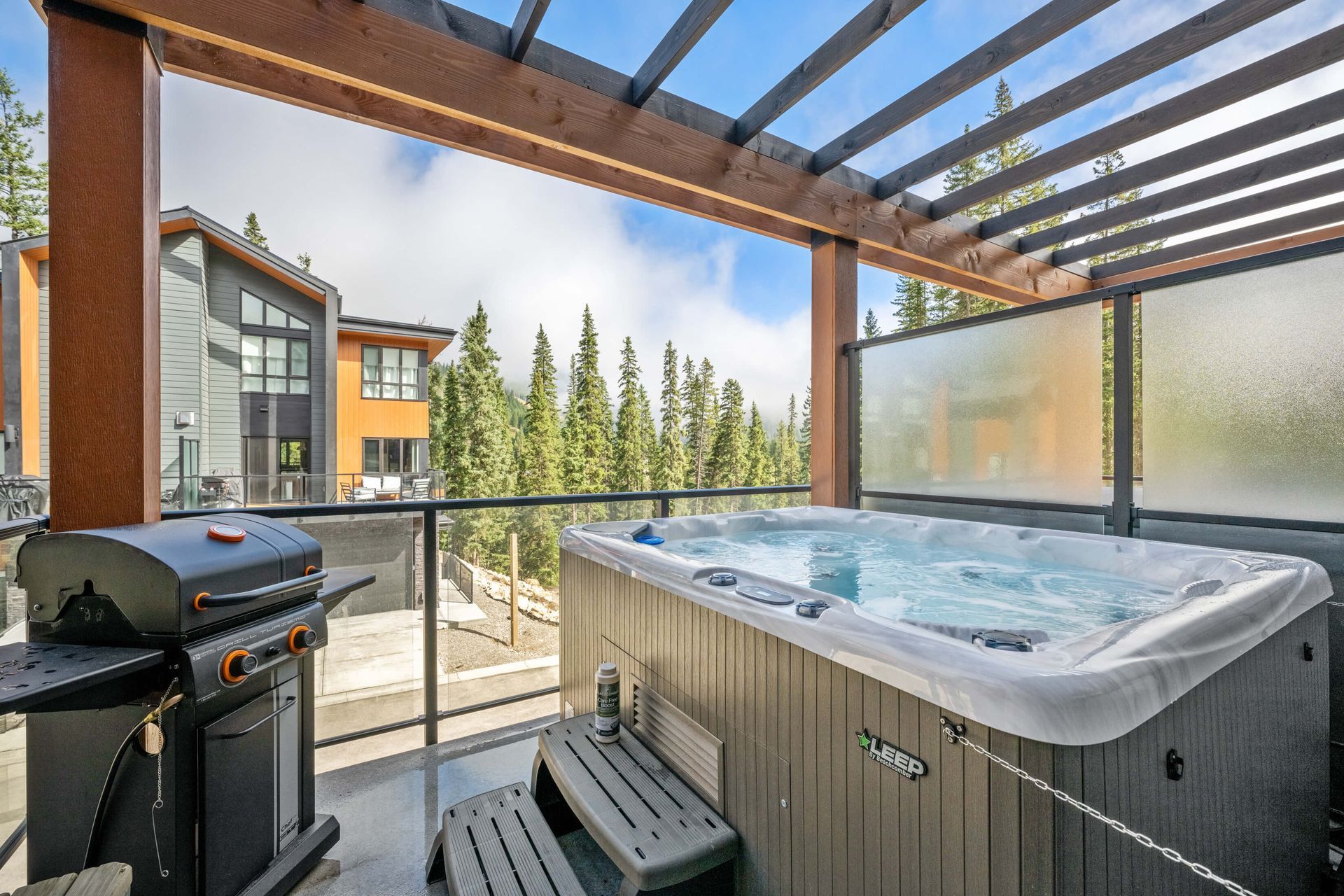 A hot tub is sitting on a balcony next to a grill.