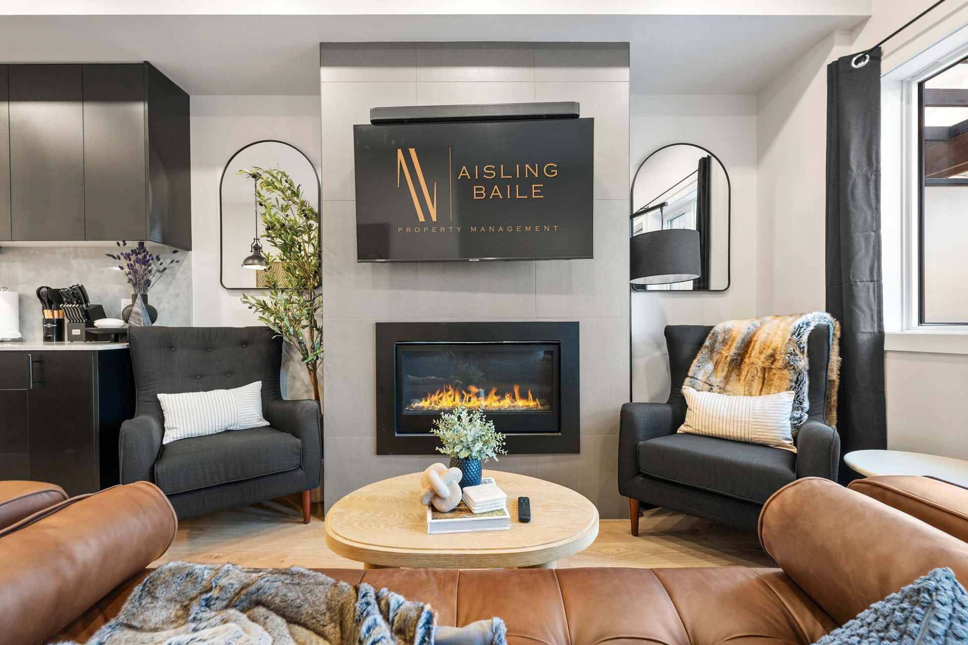 Cozy living room with fireplace, two armchairs, brown sofa, and a large TV.
