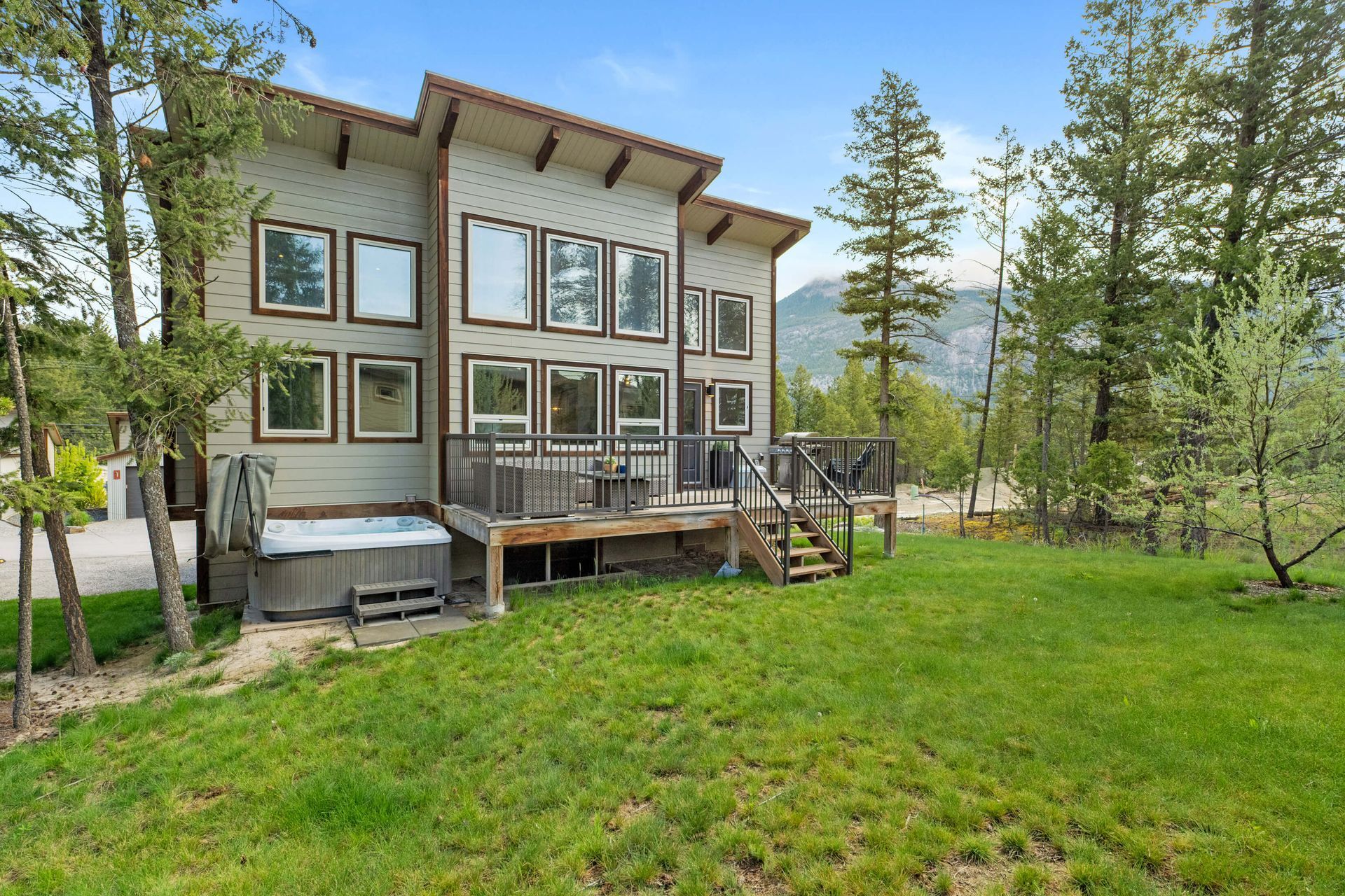 A large house with a hot tub in the backyard surrounded by trees.