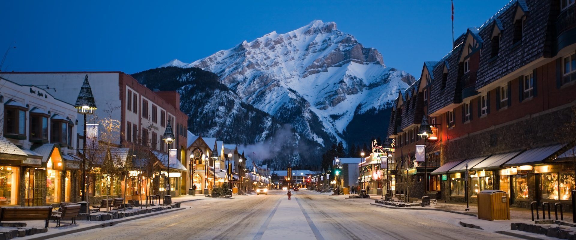 A snowy city street with a mountain in the background.