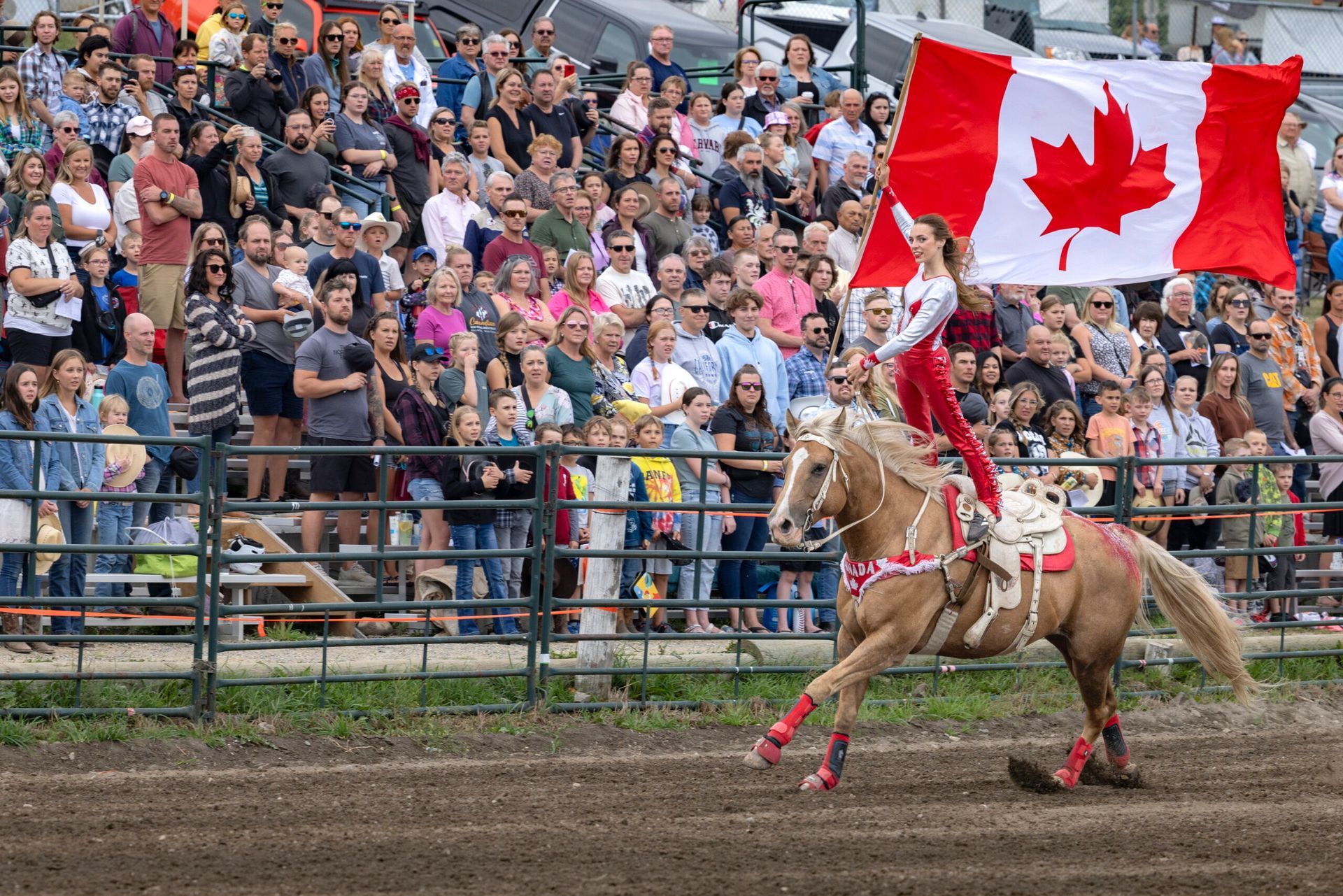 View of a woman stunt riding with a Canadian flag at the Cochrane Lions Rodeo.