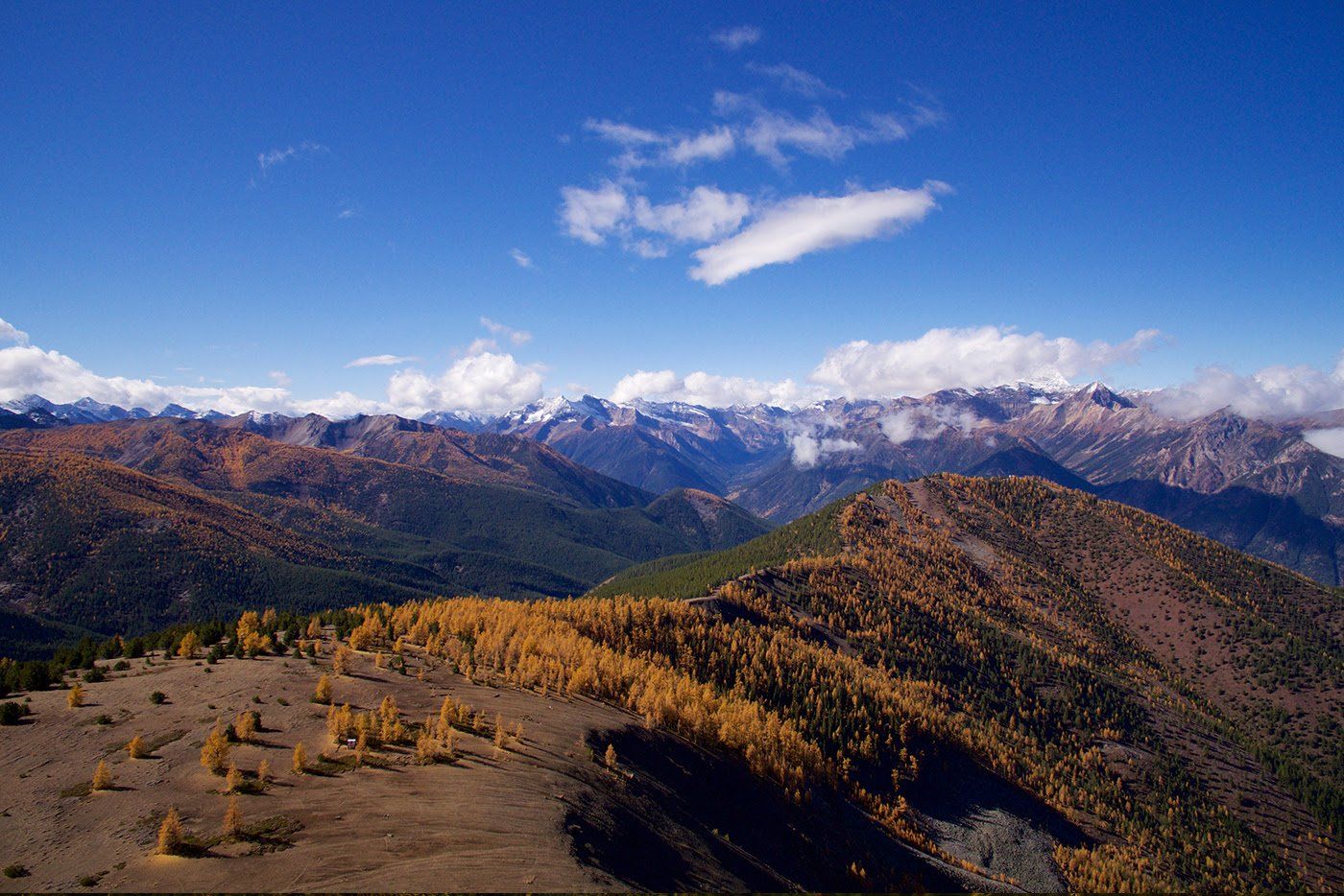 A view of a mountain range with a blue sky and clouds