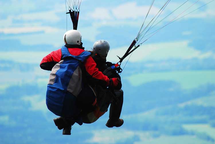 A man and a woman are parasailing in the sky