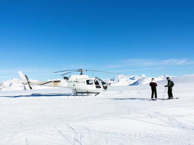 A helicopter is sitting on top of a snow covered field.
