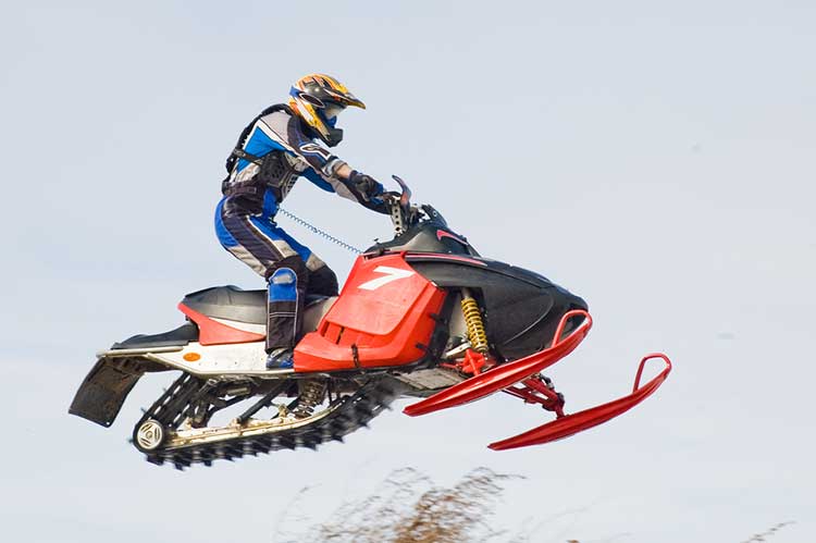 A man is riding a snowmobile in the air