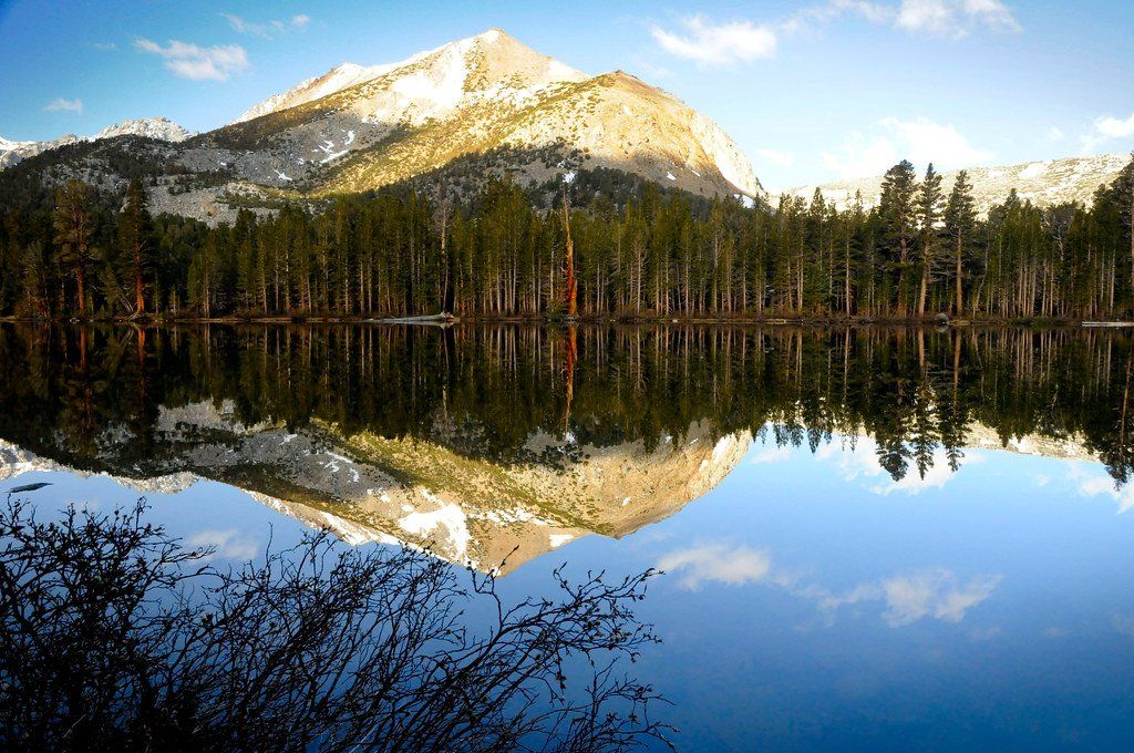 A mountain is reflected in a lake surrounded by trees