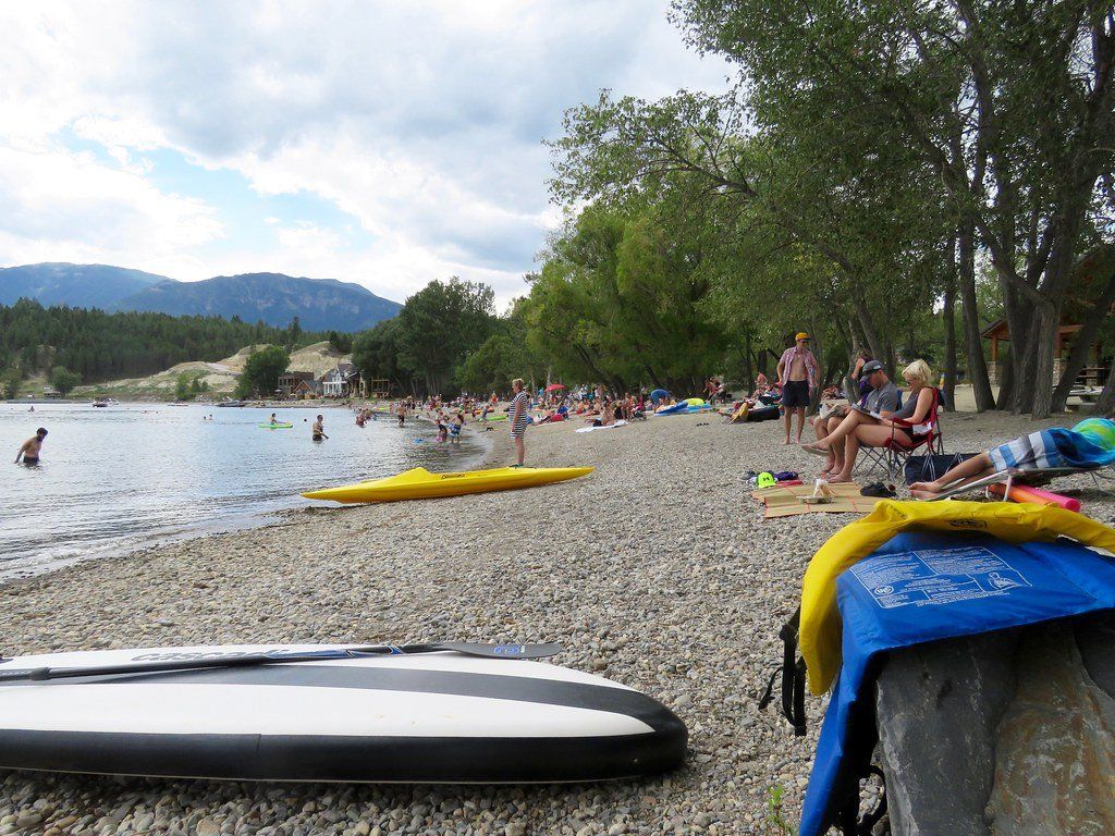 A group of people are sitting on the beach near a body of water.