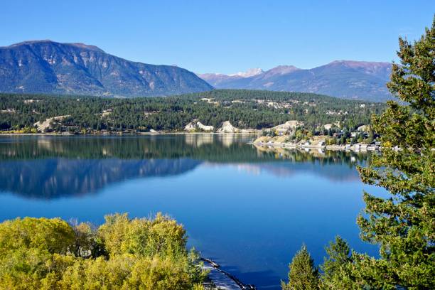 There is a lake with mountains in the background and trees in the foreground.