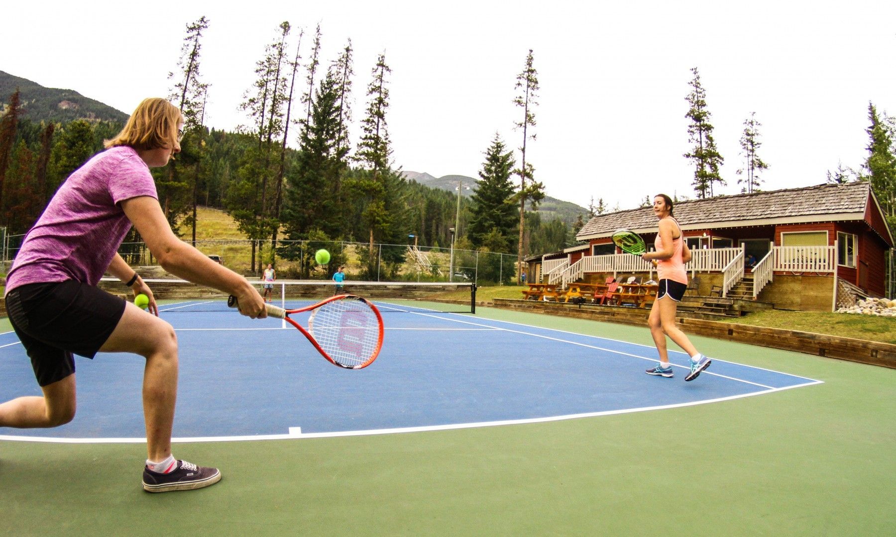 Group of young adults playing tennis in Panorama Mountain Resort.