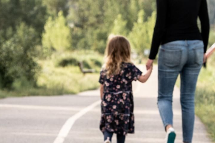 Two people walking hand in hand on a tree-lined path outdoors