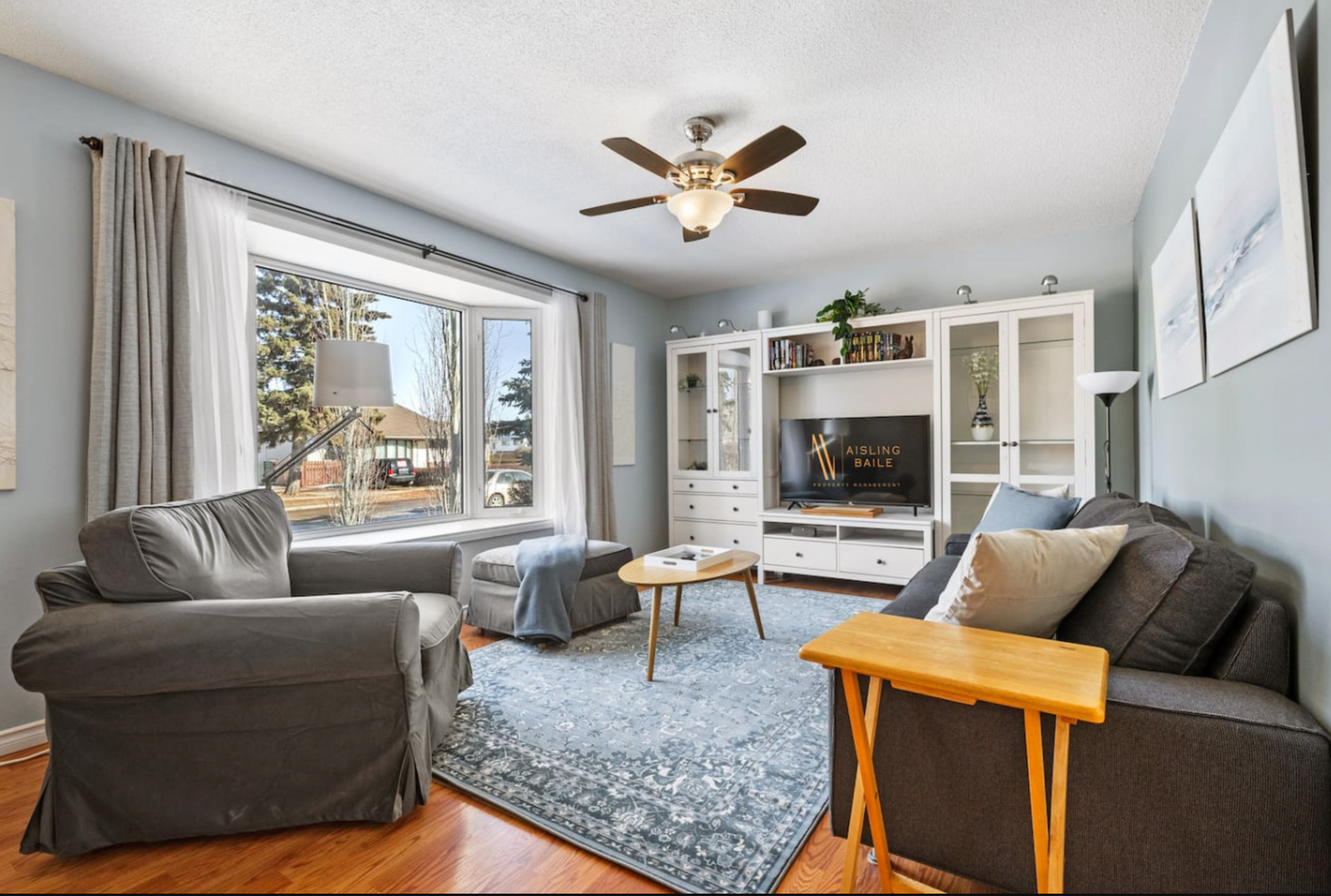 A living room with a couch , chair , table and ceiling fan.