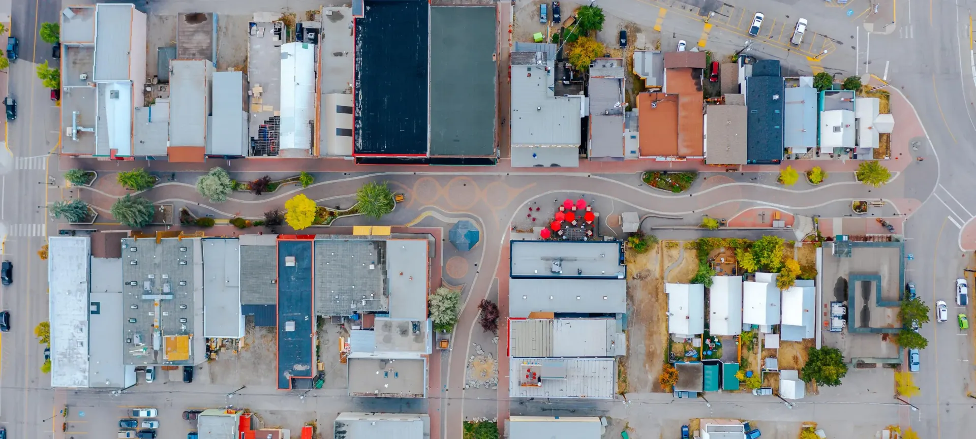 Aerial view of a city street with buildings and a pedestrian area in a roundabout.