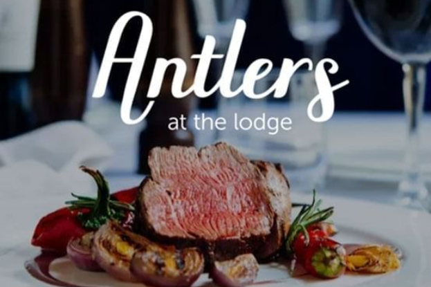 Antlers at the lodge logo over a plated steak dish with strawberries and garnish