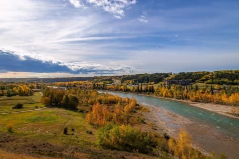 River winding through autumn fields under a partly cloudy sky