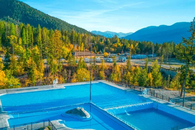 Blue swimming pool with mountains, trees, and a clear sky in the background