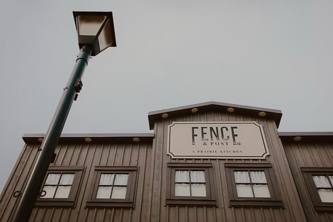Exterior of The Fence building with wooden facade, windows, and a streetlamp against a gray sky