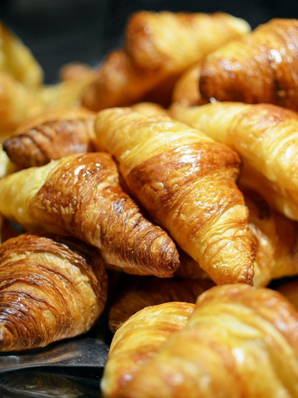 Golden, flaky croissants piled on top of each other.